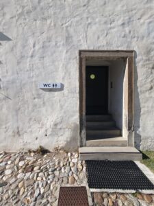 Vhodna vrata v stavbo, kjer so trenutno na voljo le sanitarije v osrednji grajski stavbi, dostopne po stopnicah.