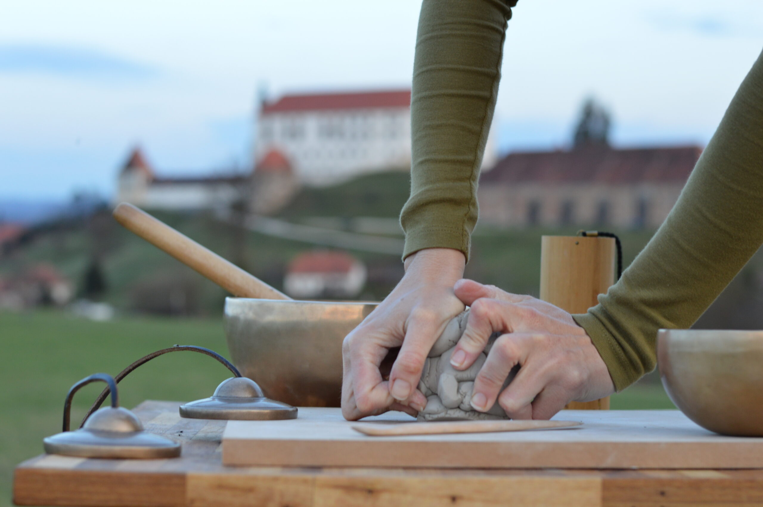 Roke, ki na mizi gnetejo glino, zraven pa so terapevtska glasbila